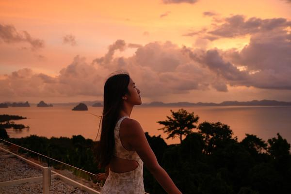 A woman looking across tropical islands at sunset, reflecting on which Southeast Asian country could feel like home