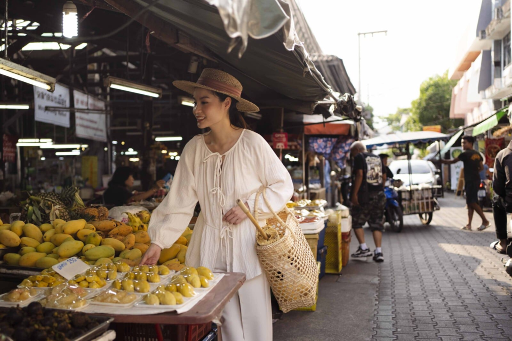 A woman shopping for fresh produce at a local market in Thailand, representing comfortable everyday life abroad on a $2,000 monthly budget